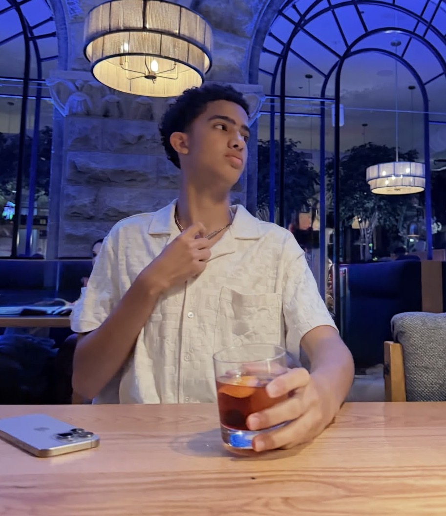 Tuff Kid at a table at night holding a drink